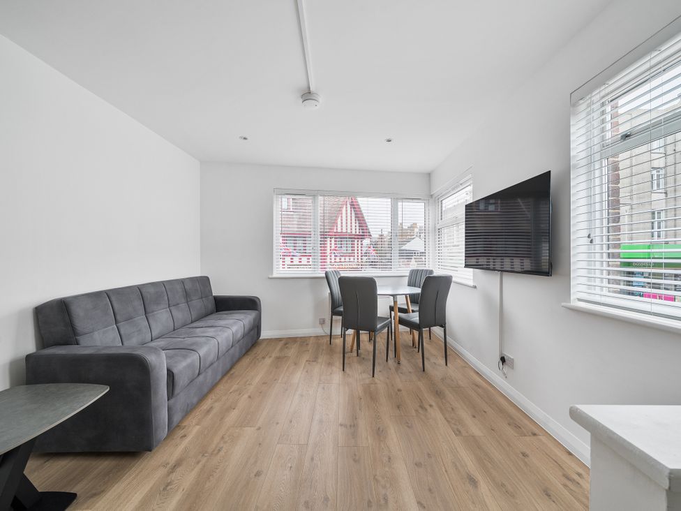 A living room with a sofa and dining table at Red Rose Apartment in Weymouth