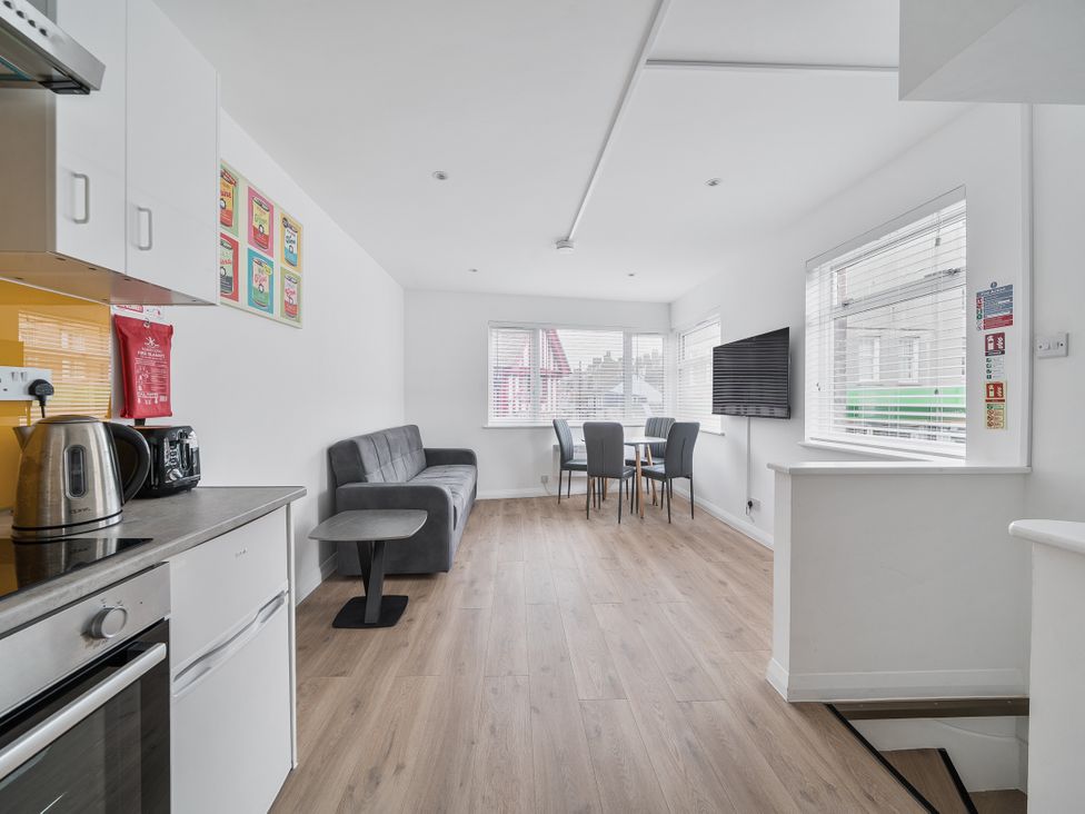 A kitchen with a dining area and a television at Red Rose Apartment in Weymouth