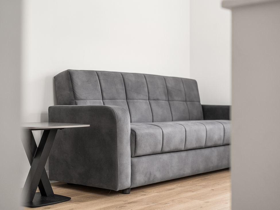 A living room with a grey sofa and a side table at Red Rose Apartment in Weymouth