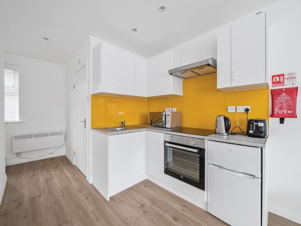 A kitchen with white cabinets and yellow backsplash at Red Rose Apartment in Weymouth