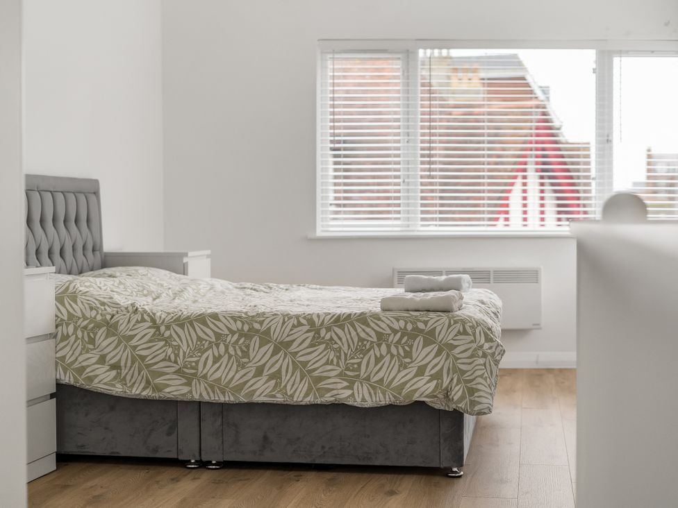 A bedroom with a bed and window at Red Rose Apartment in Weymouth