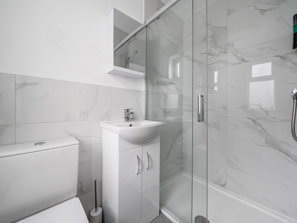 A bathroom with a shower, sink, and toilet at Red Rose Apartment in Weymouth