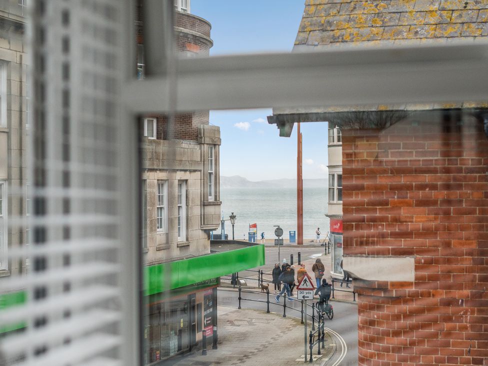 A view from a window showing a street and ocean at Red Rose Apartment in Weymouth