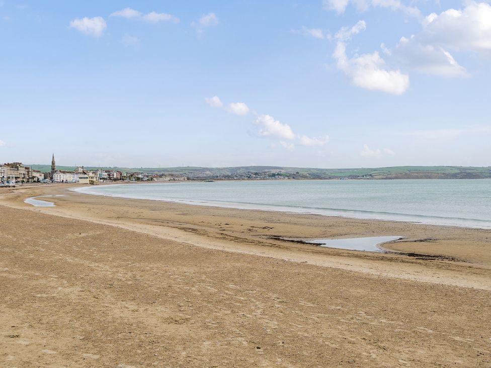A beach with water and buildings at Red Rose Apartment Weymouth