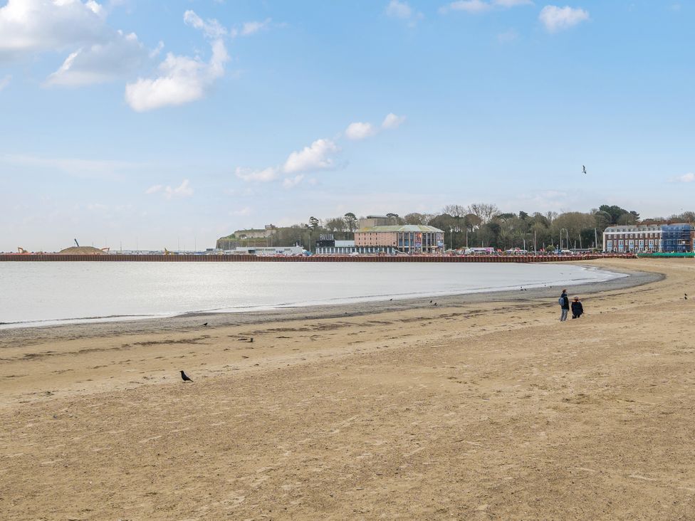 A beach with water and people walking at Red Rose Apartment in Weymouth