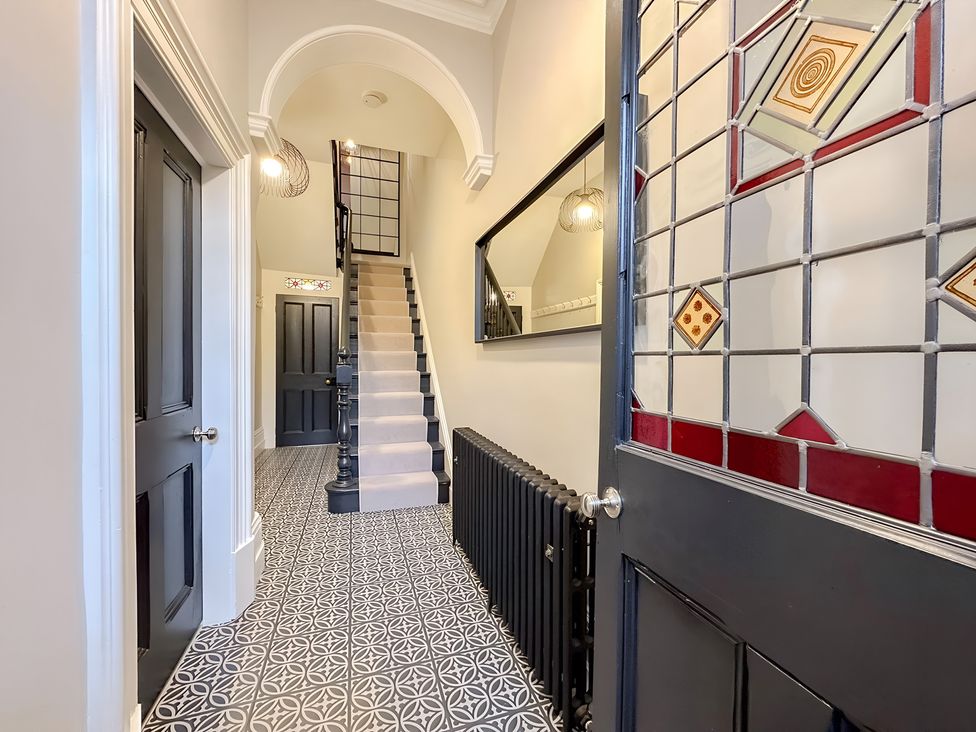 A hallway with a staircase and mirror at Victorian Beach House