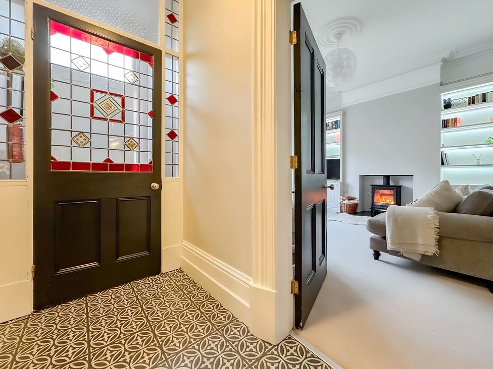 A hallway with a stained glass door and a view of a living room at Victorian Beach House