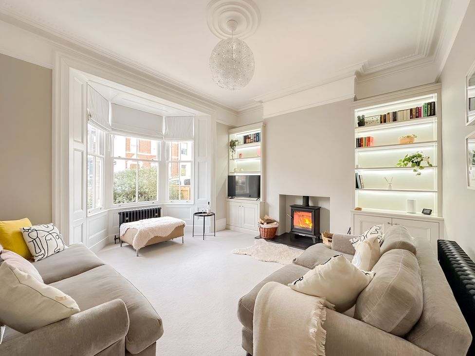 A living room with a fireplace and shelves at Victorian Beach House