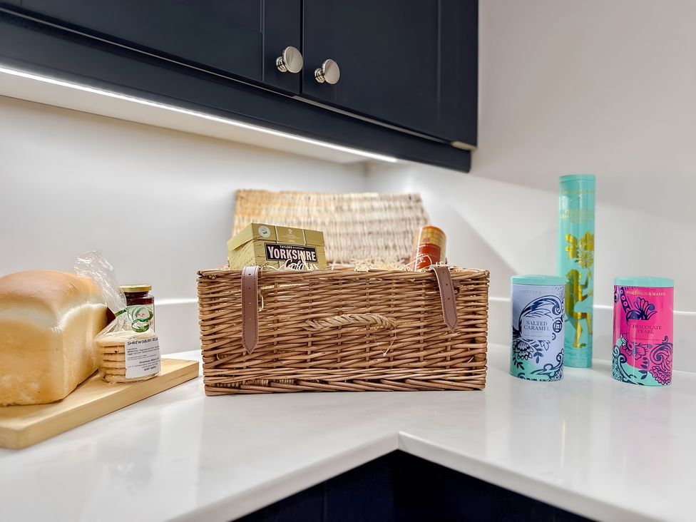 A kitchen counter with a loaf of bread, a basket, and various jars at Victorian Beach House
