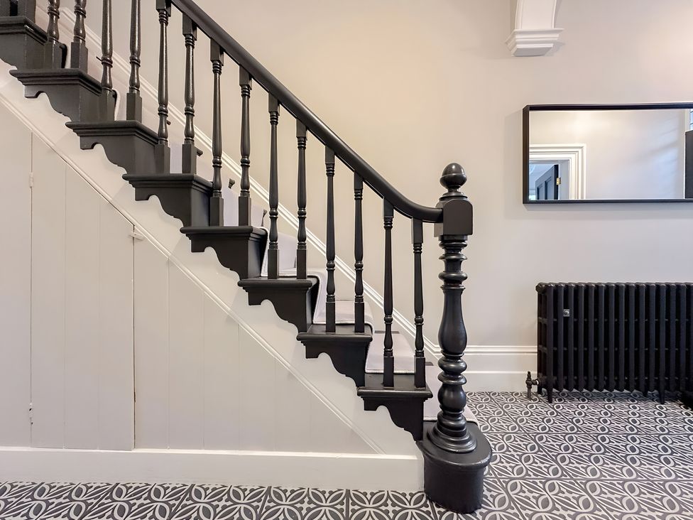 A staircase with black handrails and a mirror in a hallway at Victorian Beach House