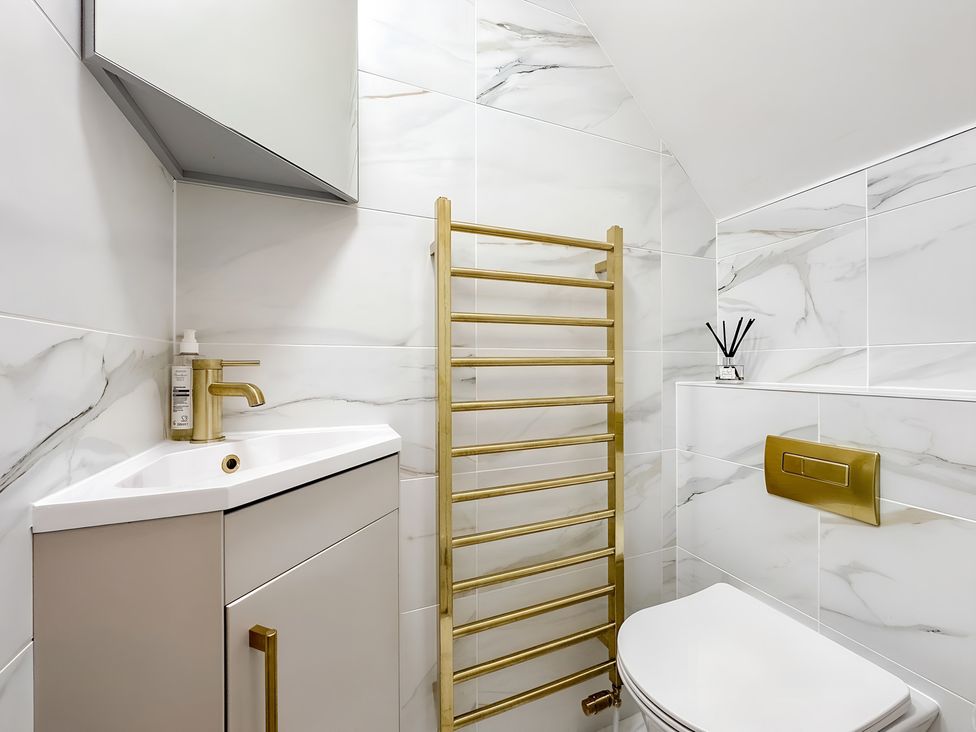 A bathroom with a sink, toilet, towel rail, and mirror at Victorian Beach House
