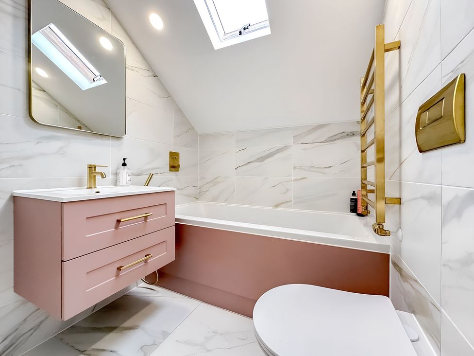 A bathroom with a bathtub, sink, and toilet at Victorian Beach House