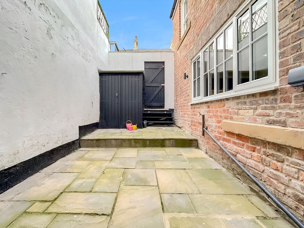 An outdoor area with paving stones and a black door at Victorian Beach House 