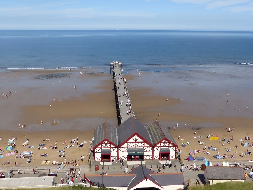 A beach with a pier and people at Victorian Beach House 