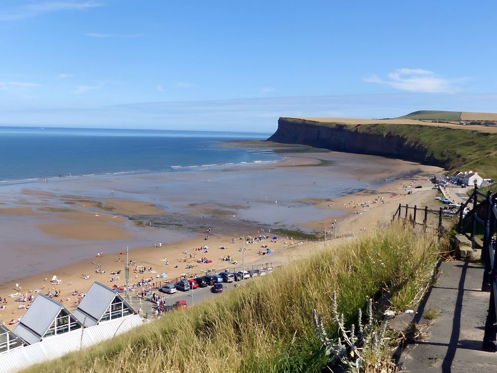 A beach view with a cliff and people at the shoreline at Victorian Beach House