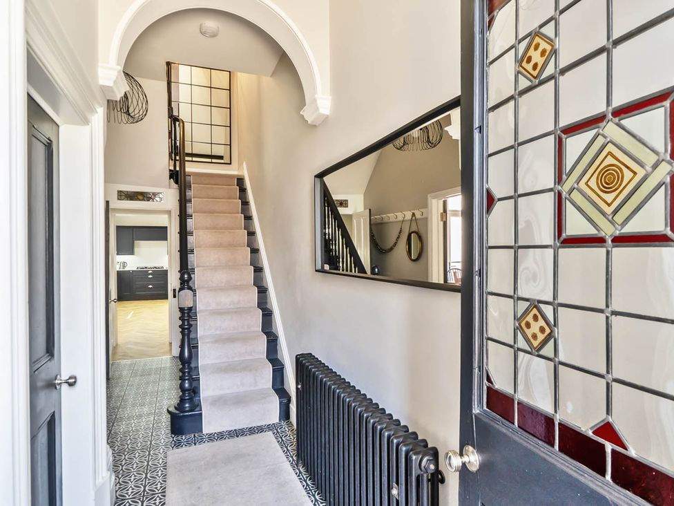 A hallway with stairs and a mirror at Victorian Beach House, Saltburn-By-The-Sea