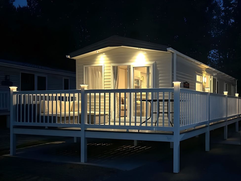 A mobile home exterior with a deck and furniture at Pine 48