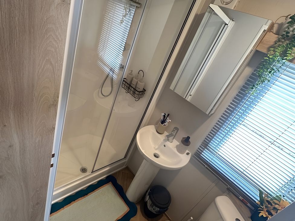 A bathroom with a shower, sink, mirror and toilet at Pine 48