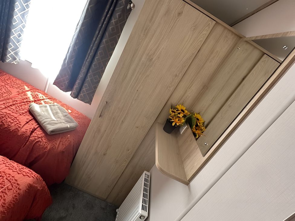 A bedroom with a bed, shelf, and flowers at Pine 48