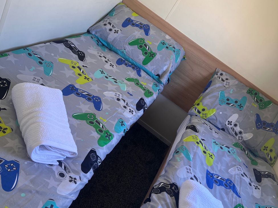 A bedroom with two beds and patterned bedding featuring game controllers at 214 Oaklands Area