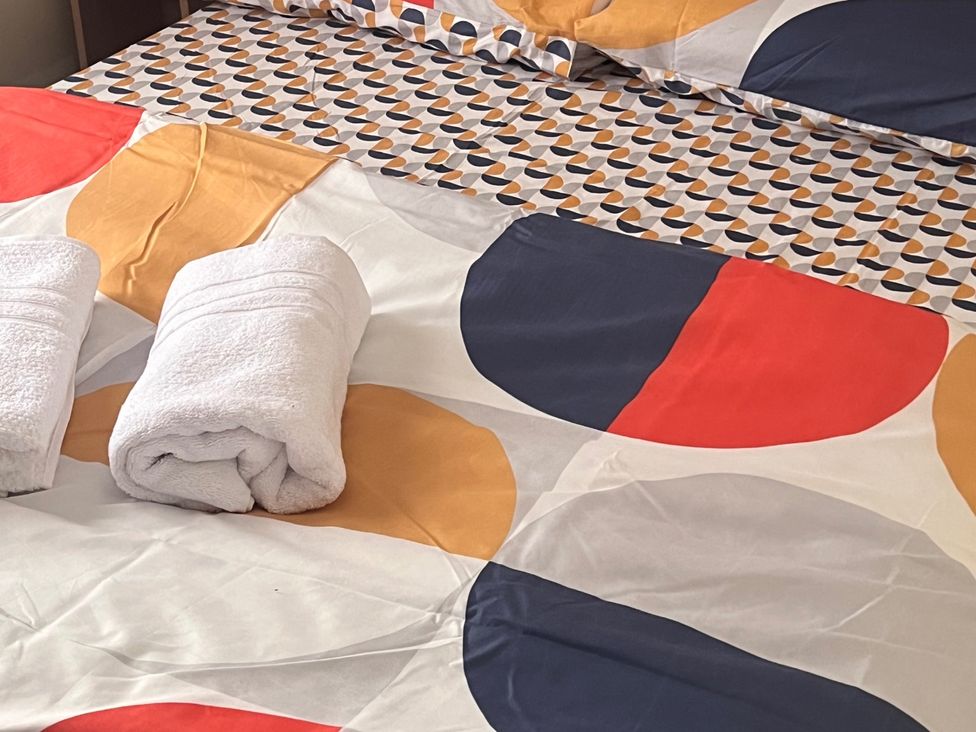 A bed with patterned bedsheet and rolled towels at 214 Oaklands Area