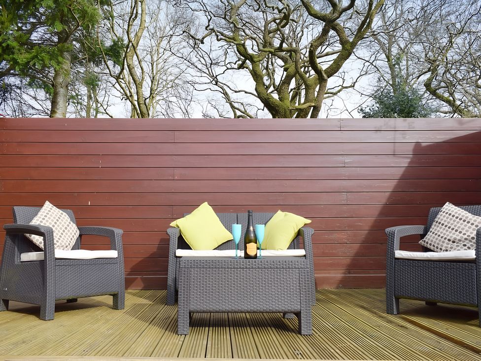 Outdoor seating area with a table and cushions at Gisburn Forest Lodge