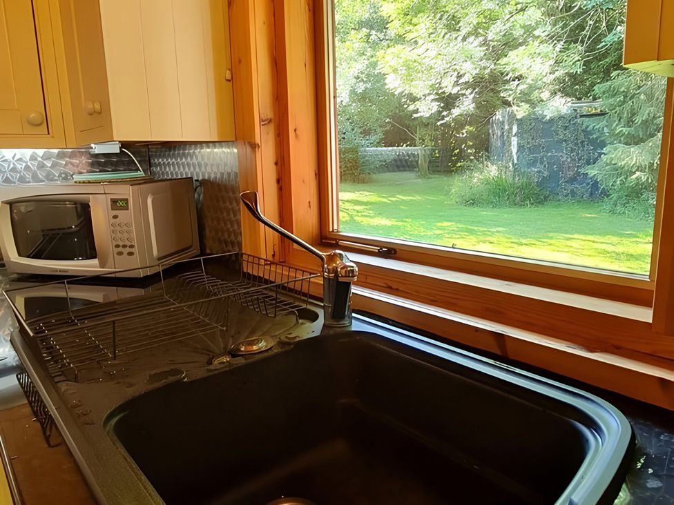 A kitchen with a sink, microwave, and window at Gisburn Forest Lodge