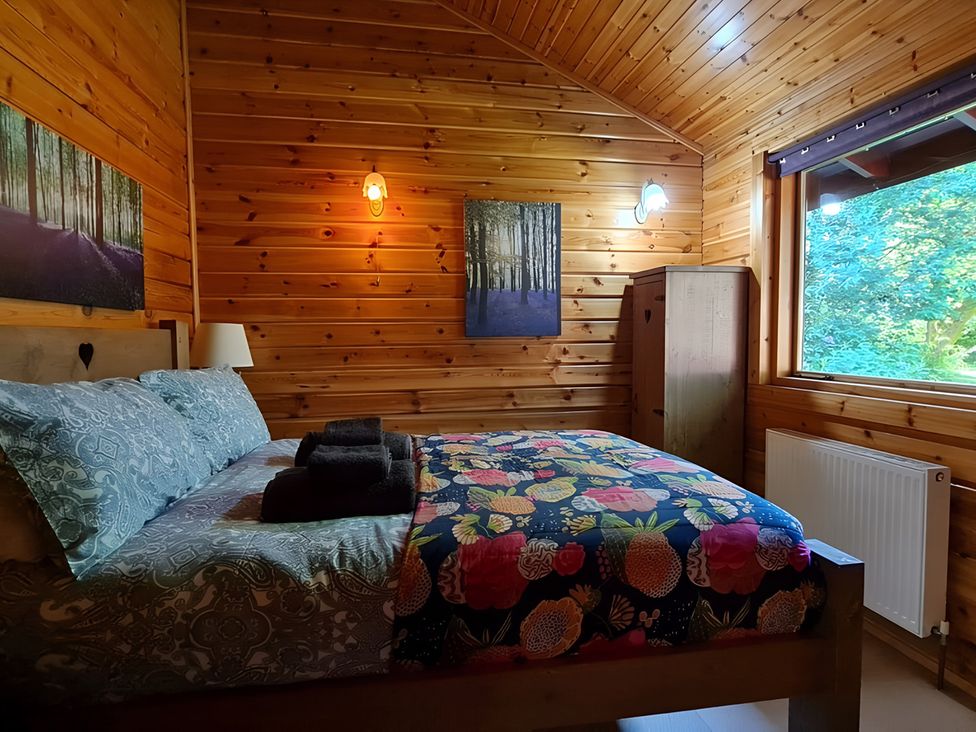 A bedroom with a bed and wardrobe at Gisburn Forest Lodge