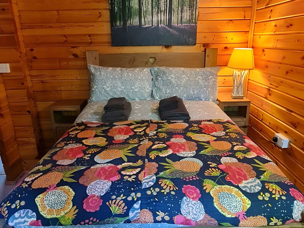 A bedroom with a bed and wooden walls at Gisburn Forest Lodge