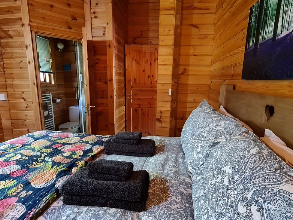 A bedroom with a bed towels and door leading to bathroom at Gisburn Forest Lodge