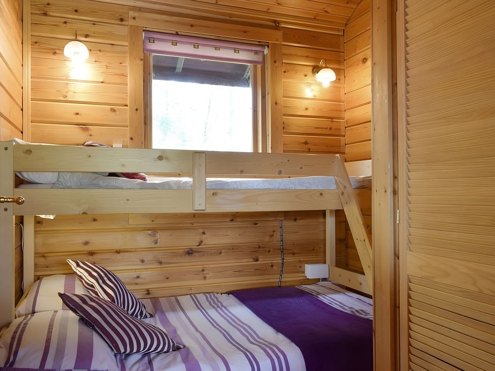 A bedroom with a bunk bed and a double bed at Gisburn Forest Lodge