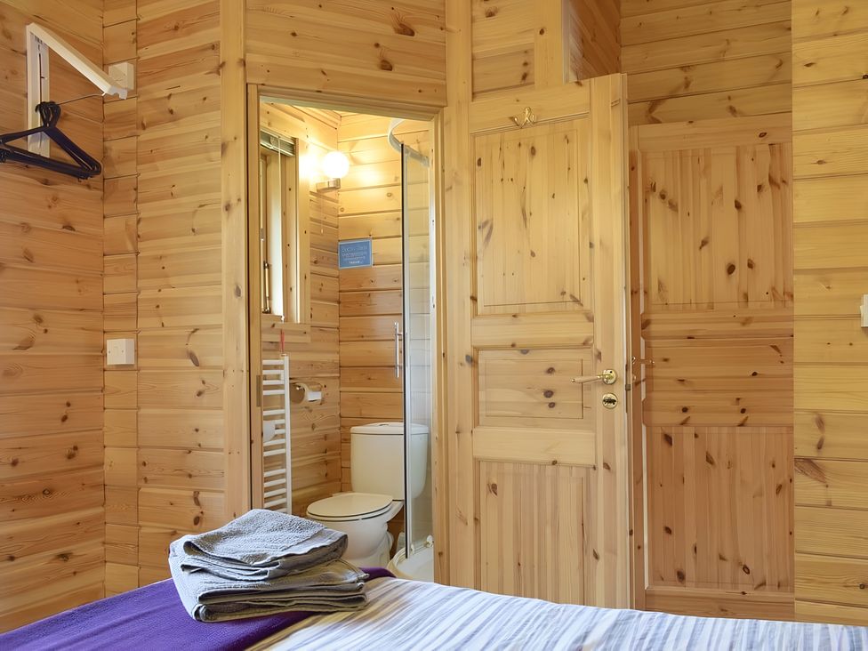 A bathroom with a toilet and shower visible from a room at Gisburn Forest Lodge