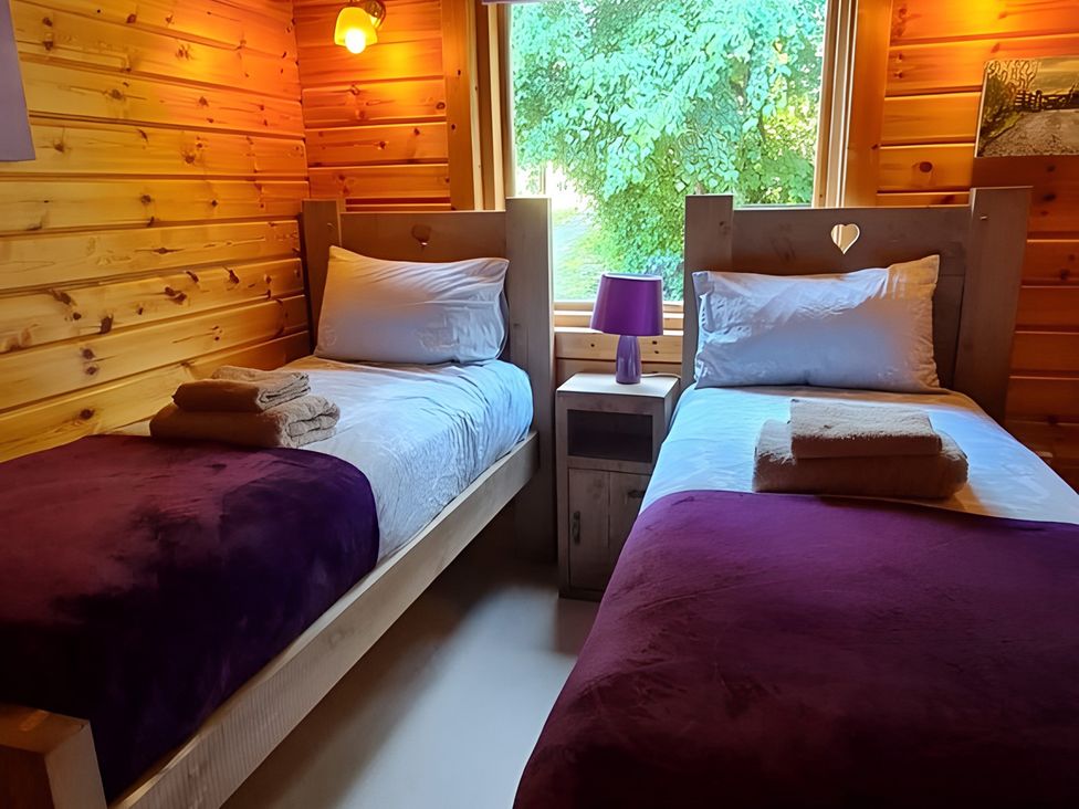 A bedroom with two beds and a window at Gisburn Forest Lodge