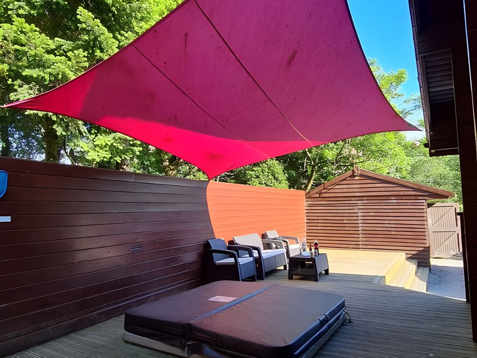 An outdoor area with seating and a sunshade at Gisburn Forest Lodge