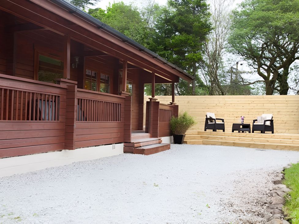 An outdoor area with a wooden cabin and seating at Gisburn Forest Lodge
