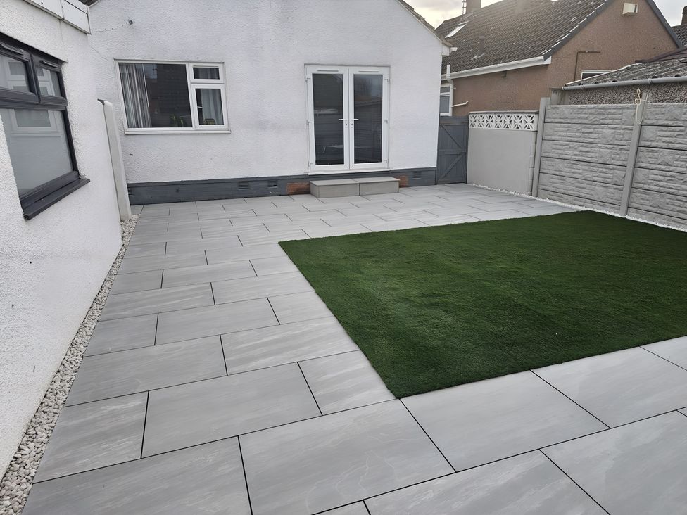 A garden with a paved patio and artificial grass at 58 Clifton Rise