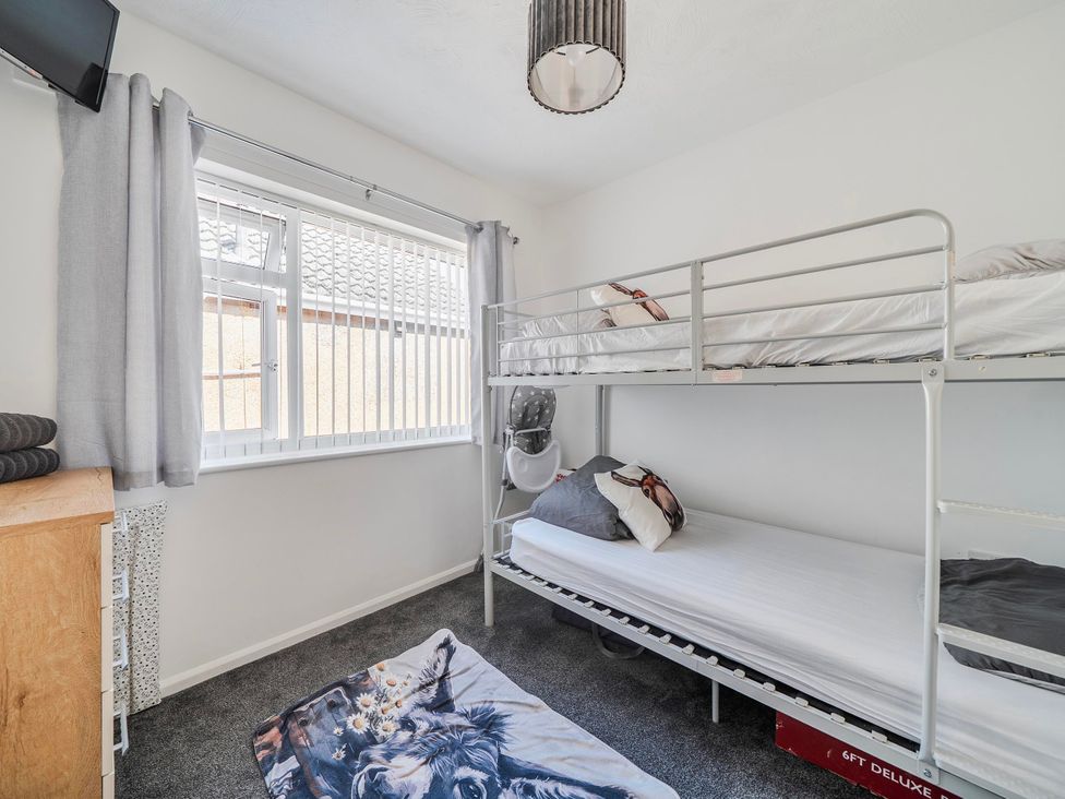 A bedroom with a bunk bed and a window with curtains at 58 Clifton Rise Abergele