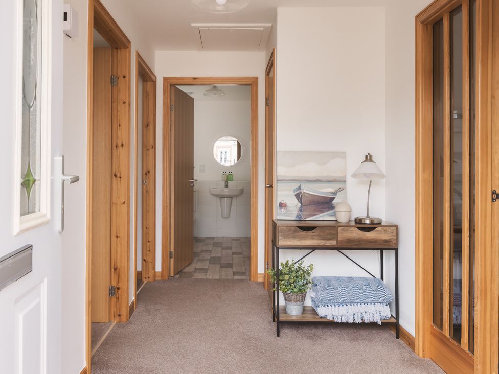 A hallway with a console table and a bathroom entrance at Acorn Court