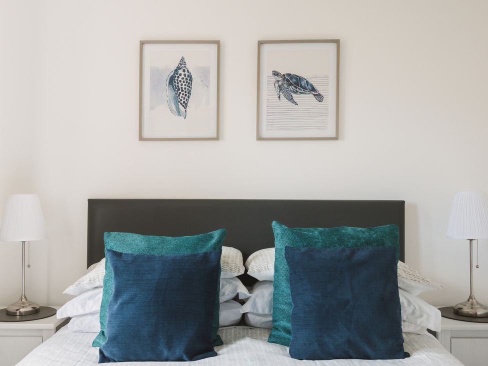 A bedroom with a bed, pillows, and wall art at Acorn Court
