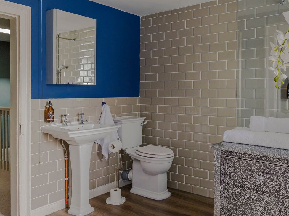 A bathroom with a sink, toilet, mirror, and storage unit at Stay Robun
