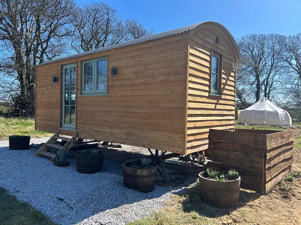 A wooden tiny house with stairs and planters at Y Nyth 
