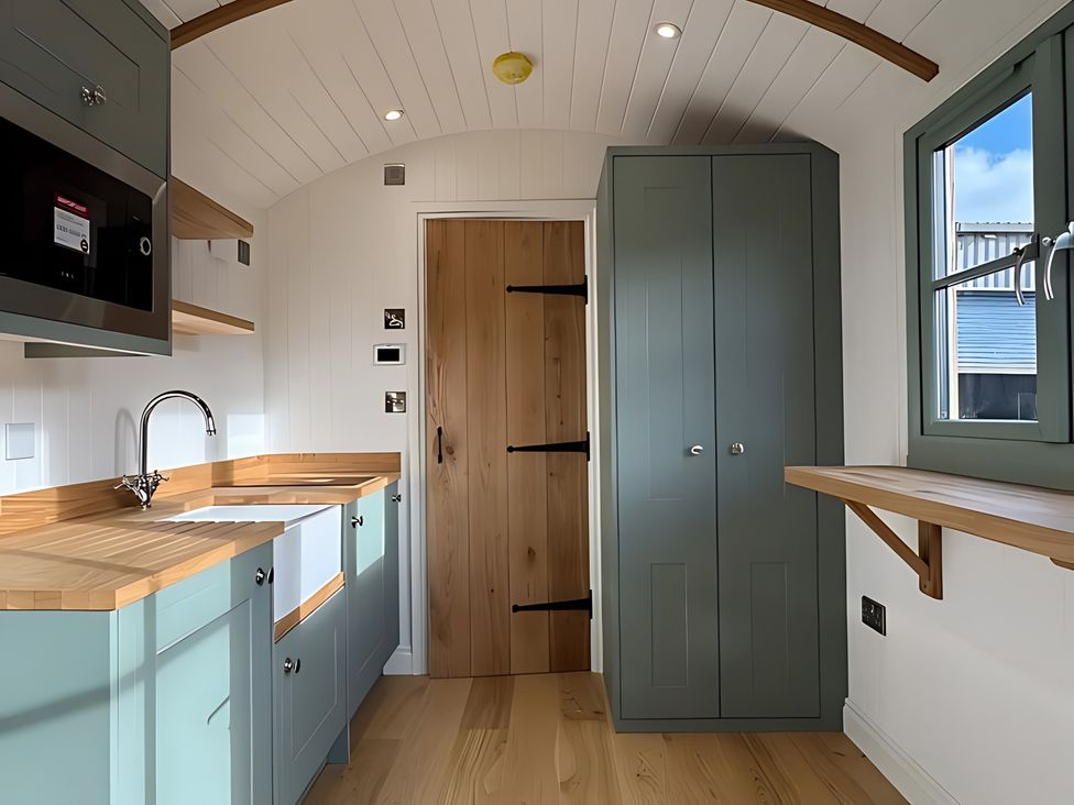 A kitchen with a sink, microwave, and cabinet at Y Nyth