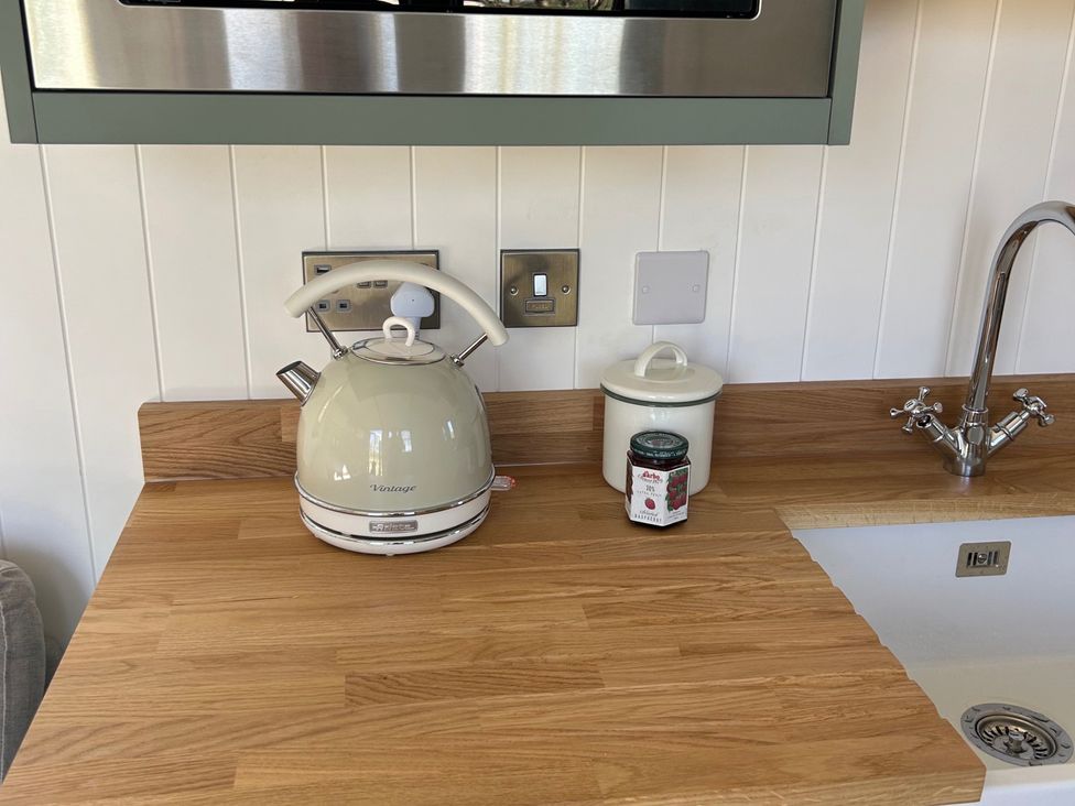 A kitchen with a kettle and jars on a wooden countertop at Y Nyth 