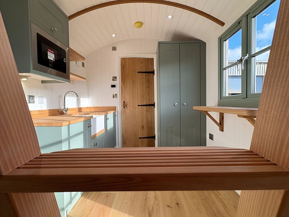 A kitchen with cabinets and a door at Y Nyth