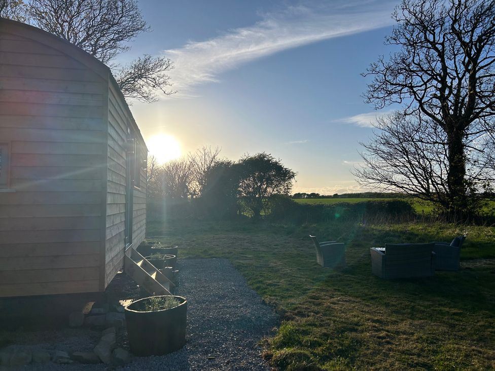 A wooden structure beside a gravel pathway with chairs at Y Nyth in 