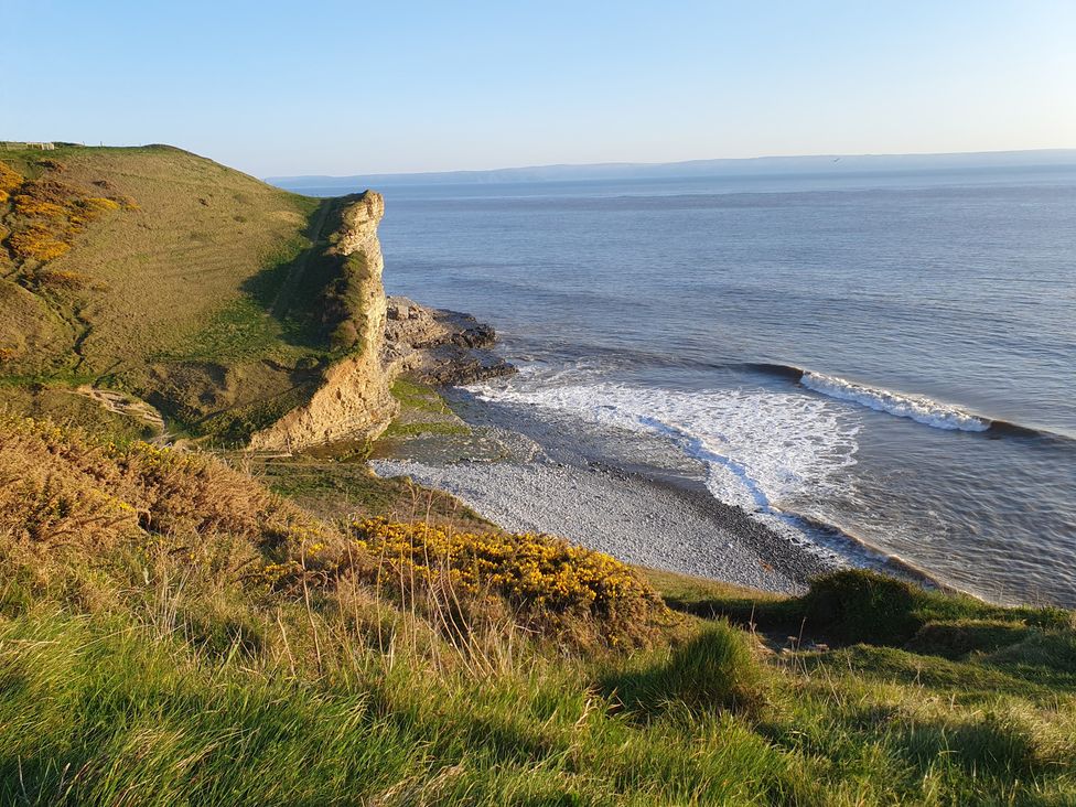 A cliff overlooking the sea with rocks and grass at Y Nyth in 