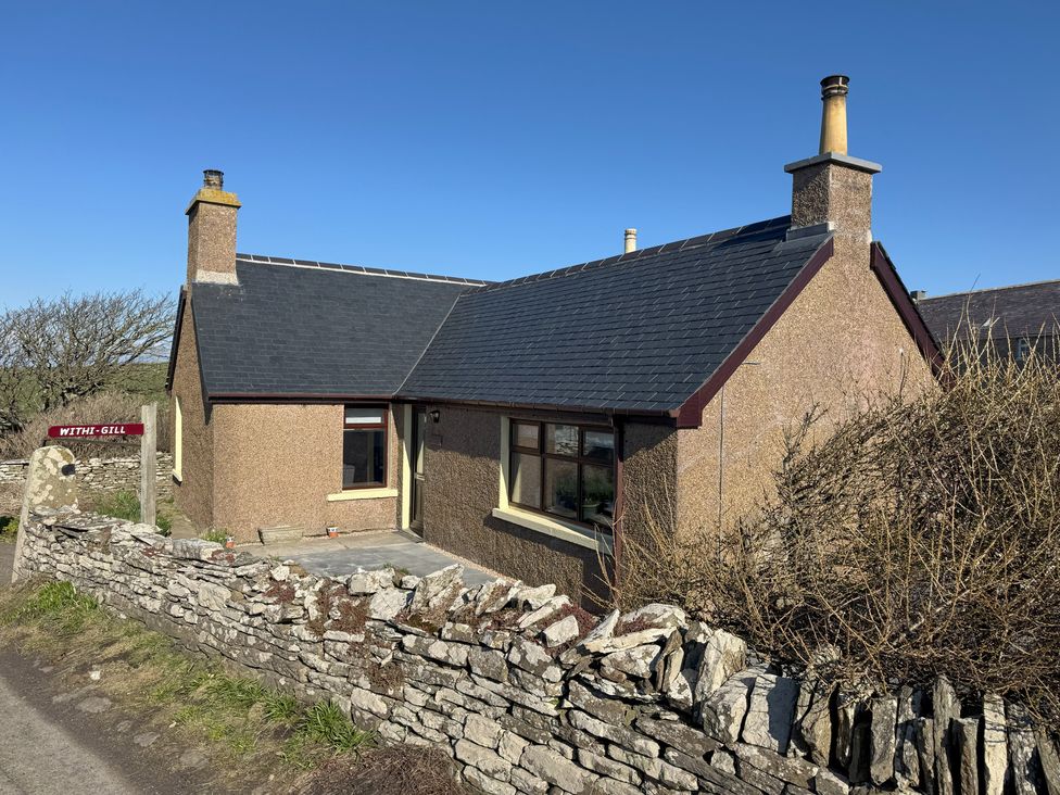A house with a chimney and stone wall at Withi-Gill