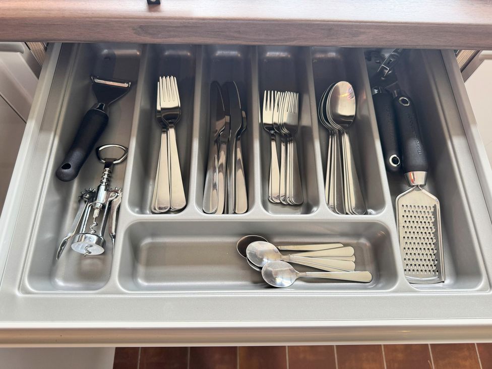A kitchen drawer with assorted utensils including forks, knives, and a grater at Withi-Gill