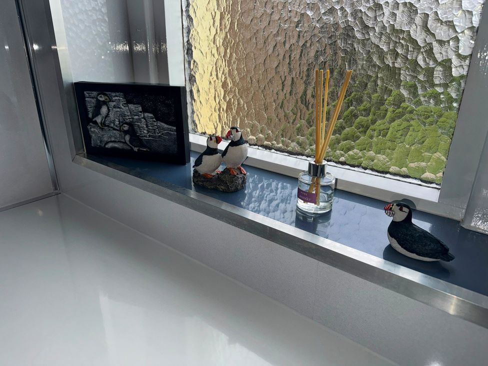 A bathroom window with decorative figures and a reed diffuser at Withi-Gill