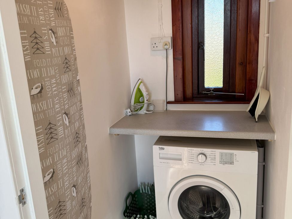 A laundry room with a washing machine and iron at Withi-Gill